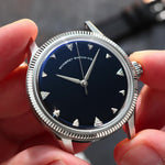 A close-up of a wristwatch with a silver-tone fluted bezel and a natural Onyx stone dial, held by two hands. Lab-grown diamond on dial.
