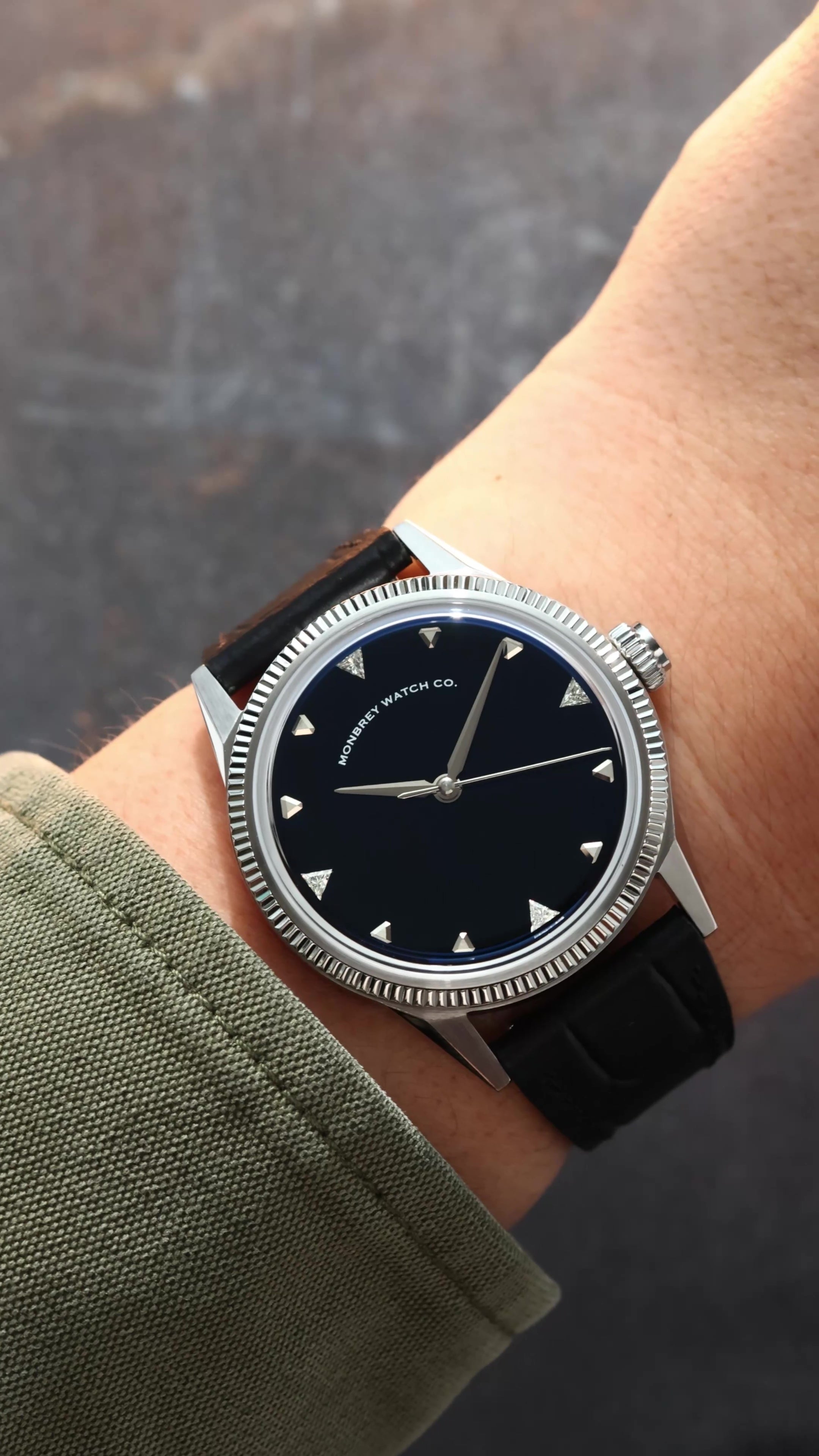 A wristwatch with a round silver-tone case and fluted bezel, and a natural Onyx stone dial, and a black croco leather strap, worn by a person in a casual setting. Lab-grown diamond on dial.
